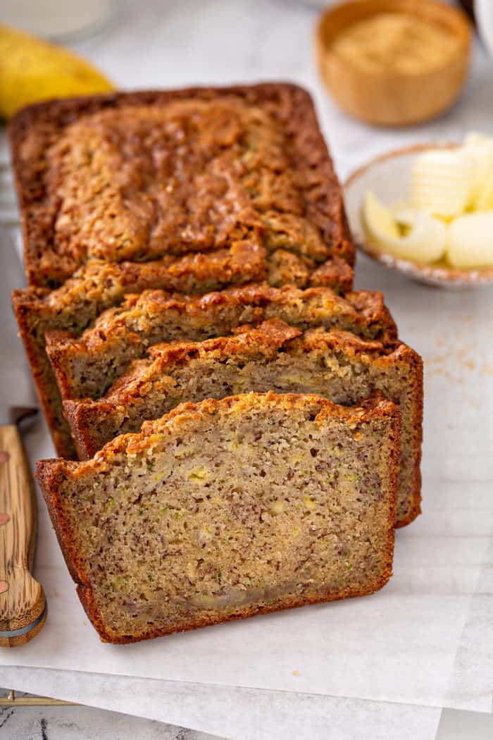 Sliced loaf of zucchini banana bread on a piece of parchment paper