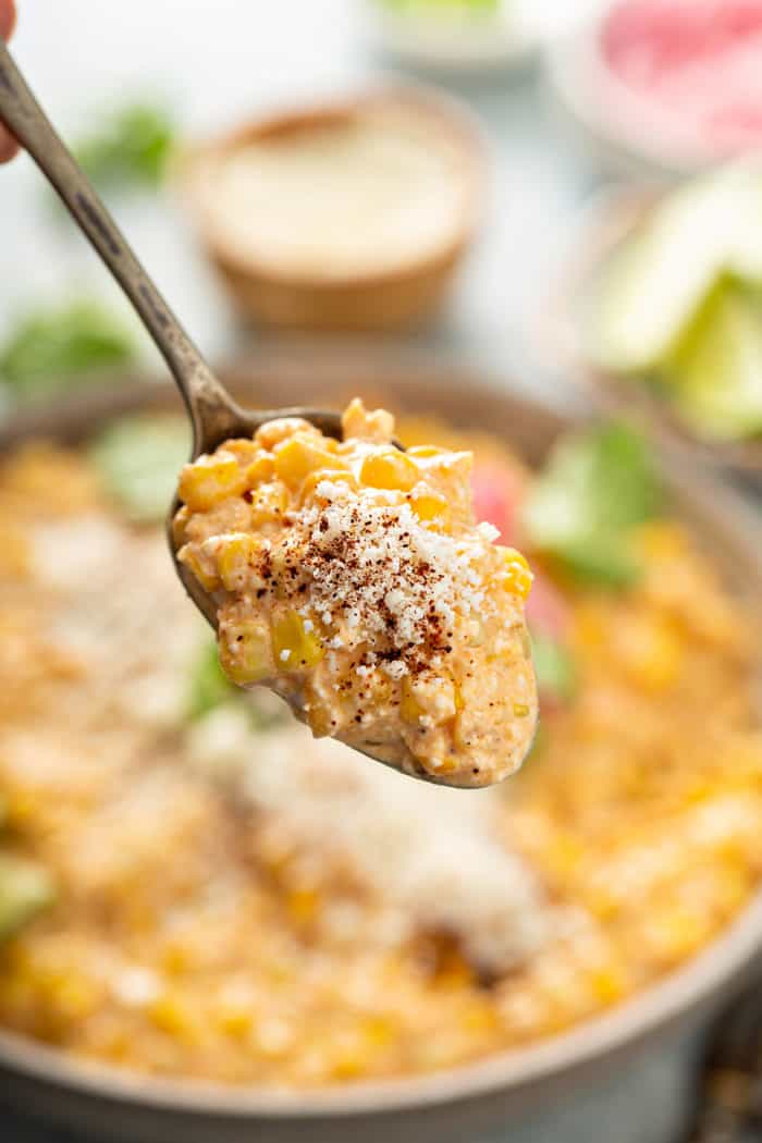 Mexican street corn salad being held up to the camera on a spoon