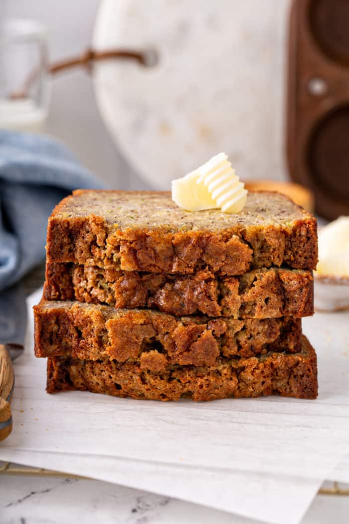 Four slices of zucchini banana bread stacked on a cutting board