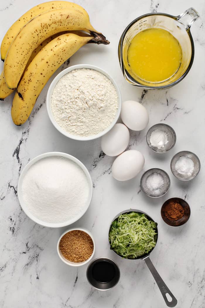 Ingredients for zucchini banana bread arranged on a marble countertop