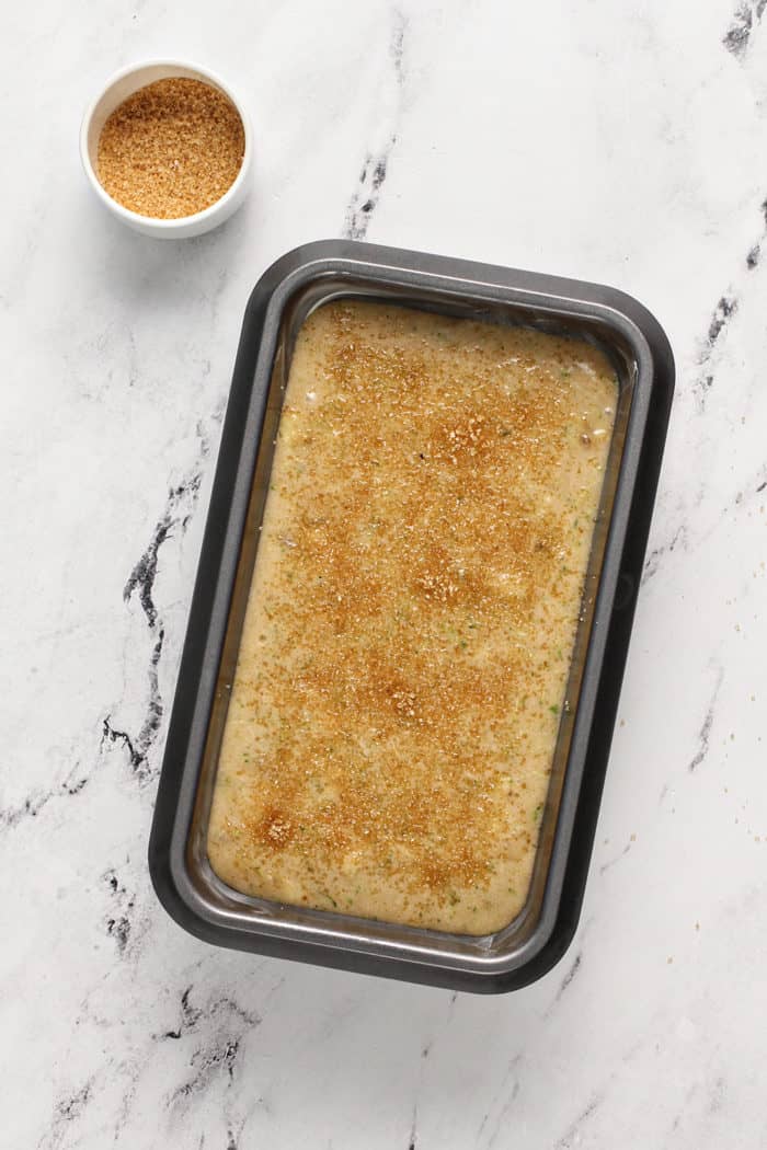 Zucchini banana bread batter in a loaf pan, sprinkled with turbinado sugar, ready to bake