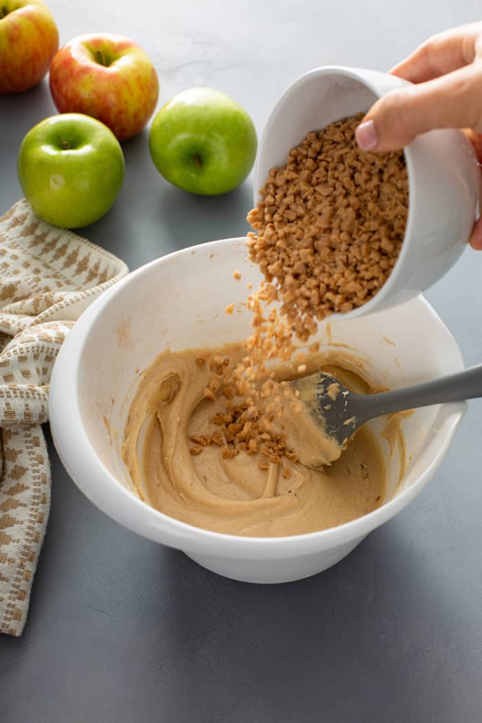 Toffee bits being added to a bowl of apple dip