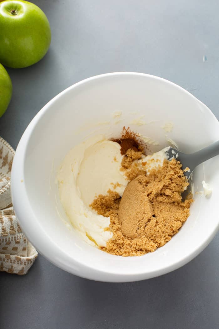 Brown sugar and vanilla being added to whipped cream cheese to make apple dip