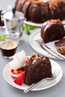 Plates of easy chocolate bundt cake next to a cake plate and cups of espresso