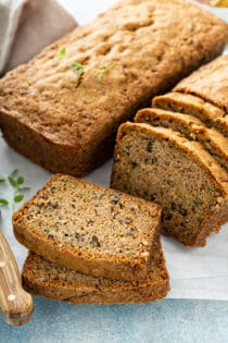 Two loaves of classic zucchini bread on a cutting board, with several slices cut from one of the loaves