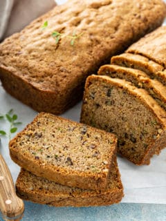 Two loaves of classic zucchini bread on a cutting board, with several slices cut from one of the loaves