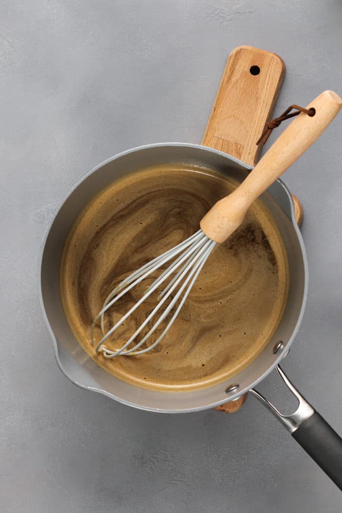 Sugar syrup for apple dumplings being whisked in a saucepan