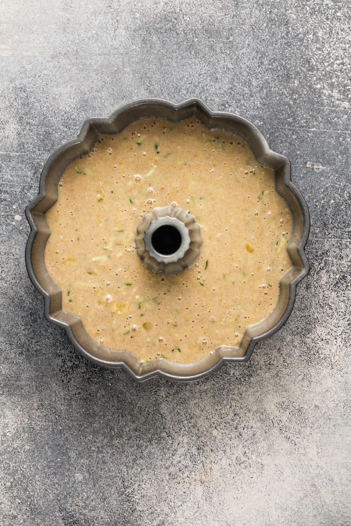 Batter for zucchini cake in a greased bundt pan, ready to bake