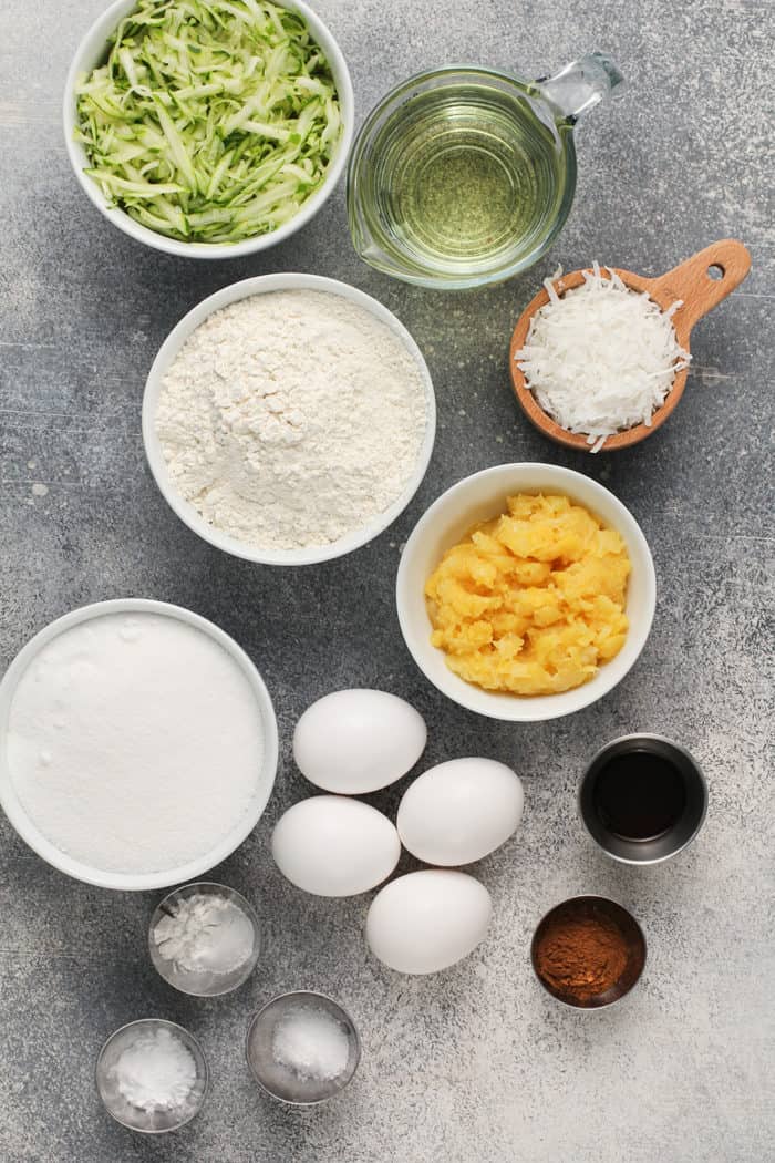 Ingredients for zucchini bundt cake arranged on a gray countertop