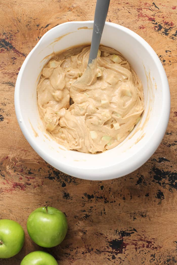 Apple coffee cake batter in a white mixing bowl on a wooden countertop