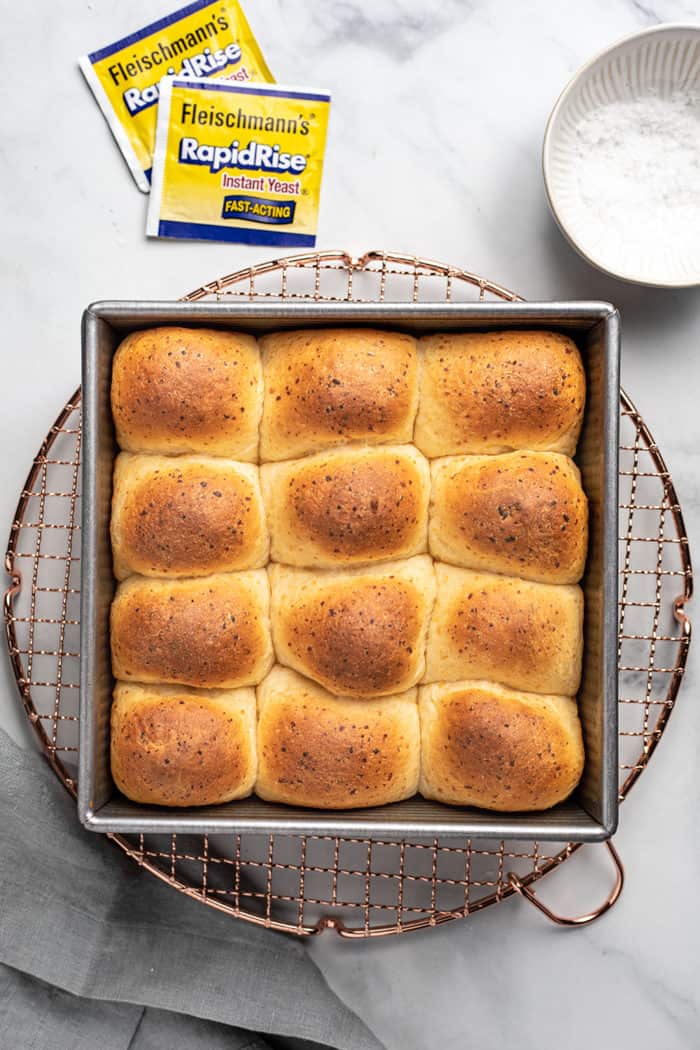 Overhead view of freshly baked cheddar dinner rolls set on a metal cooling rack