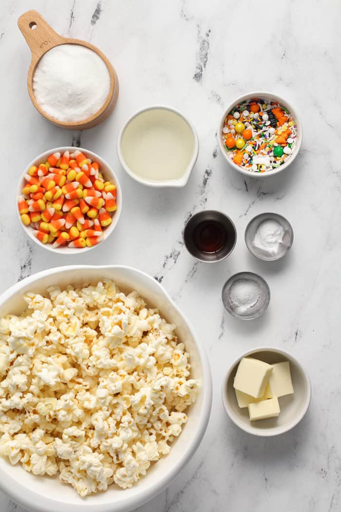 Ingredients for halloween popcorn balls arranged on a marble countertop