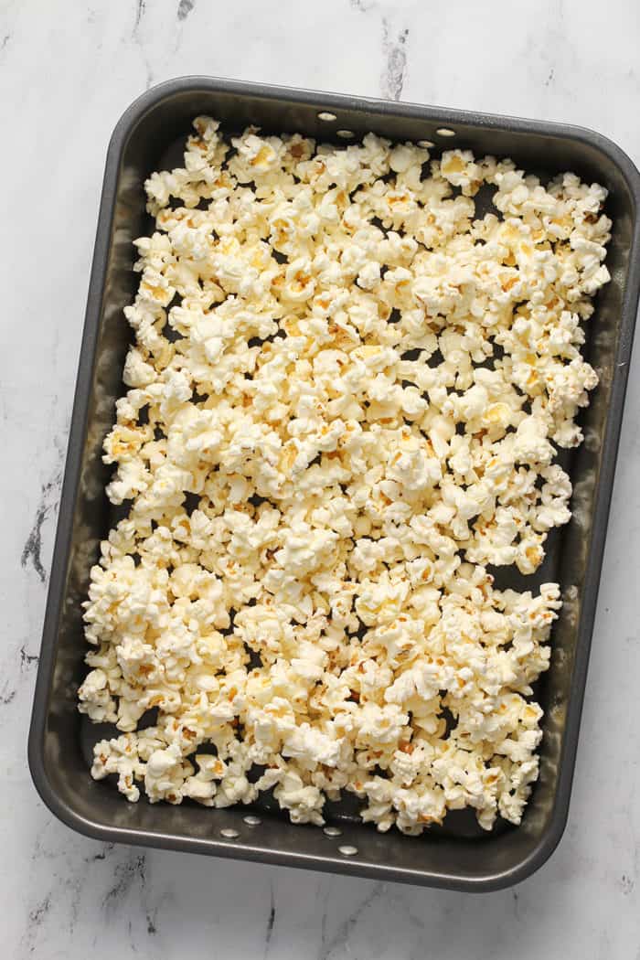 Pan of popped popcorn set on a marble countertop