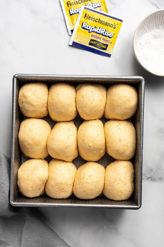 Dough for cheddar dinner rolls risen in a metal pan, ready to bake