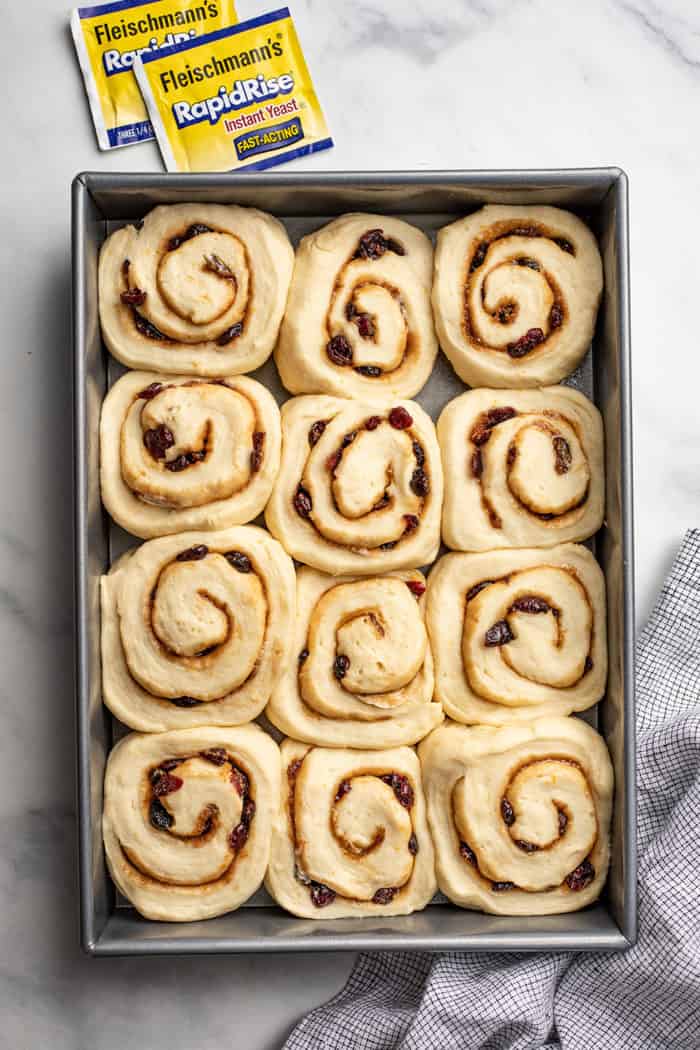 Sliced and risen cranberry orange cinnamon rolls in a baking pan, ready to bake