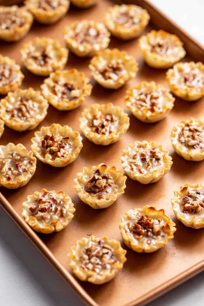 Unbaked mini pecan pies arranged on a baking sheet