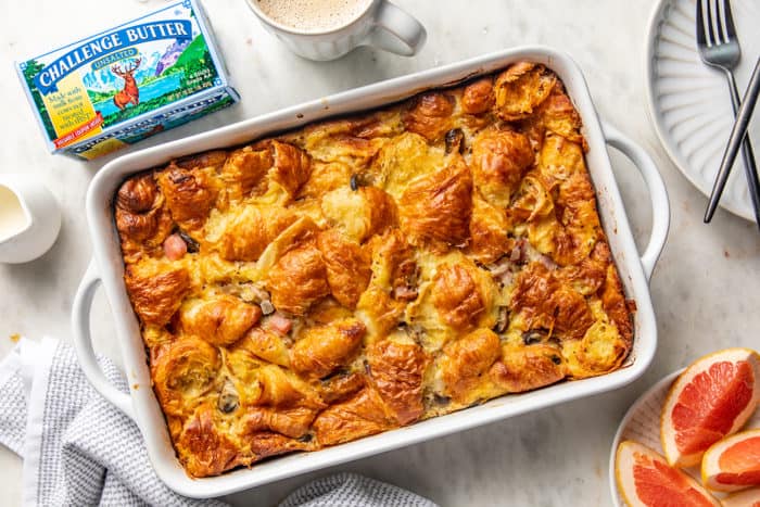 Overhead view of baked croissant breakfast casserole in a white baking dish on a marble countertop