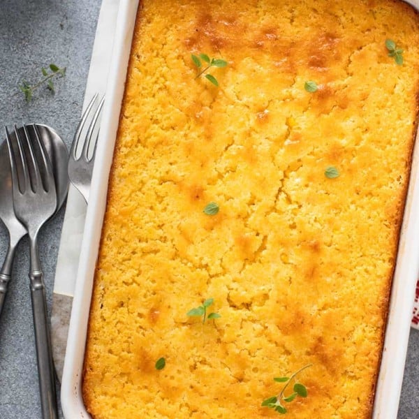 Baked jiffy corn casserole in a white baking dish, set on a gray countertop