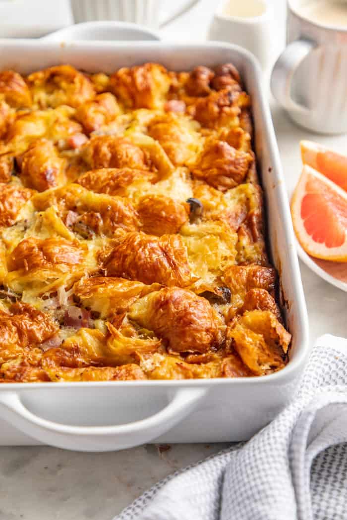 Baked croissant breakfast casserole in a white baking dish set on a white countertop