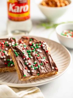 Plated peanut butter pretzel bars with corn syrup and a bowl of pretzels in the background