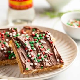 Plated peanut butter pretzel bars with corn syrup and a bowl of pretzels in the background