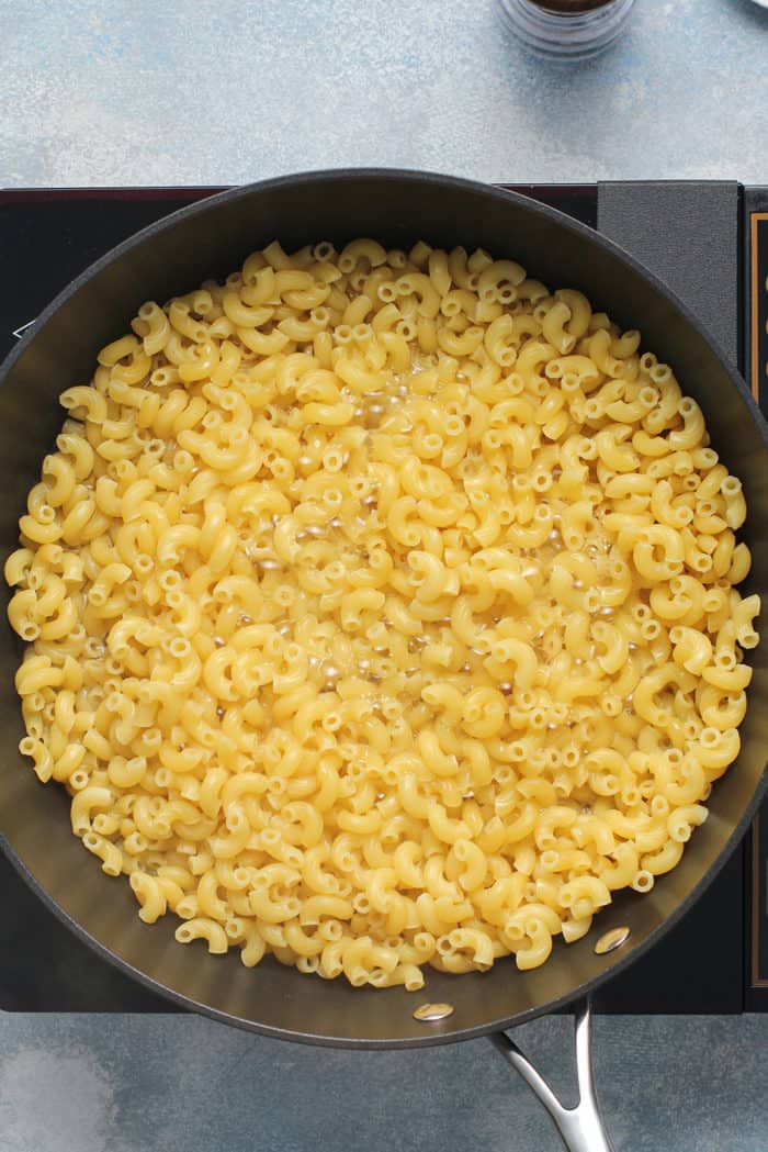 Macaroni noodles cooking in a wide skillet