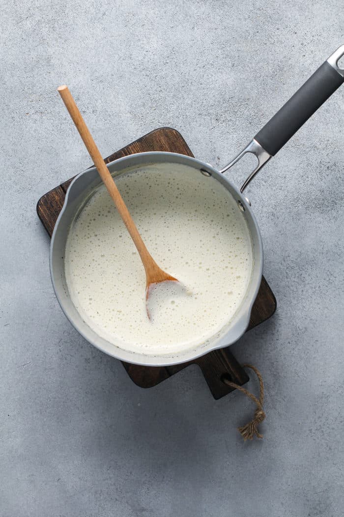 Spoon stirring cream sauce in a saucepan