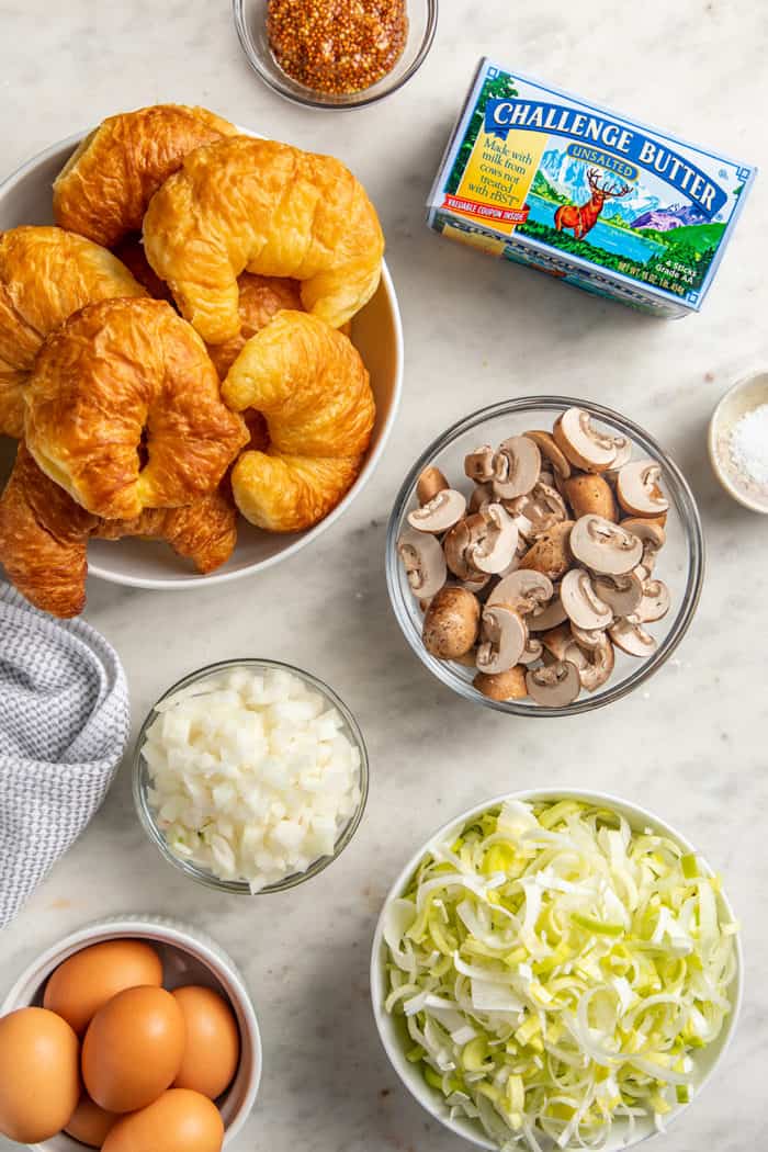 Ingredients for croissant breakfast casserole arranged on a marble countertop