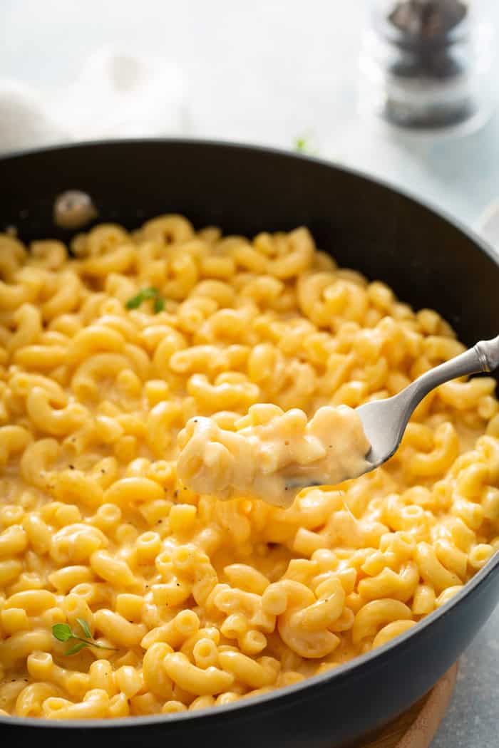 Fork lifting a bite of one pot mac and cheese out of a skillet