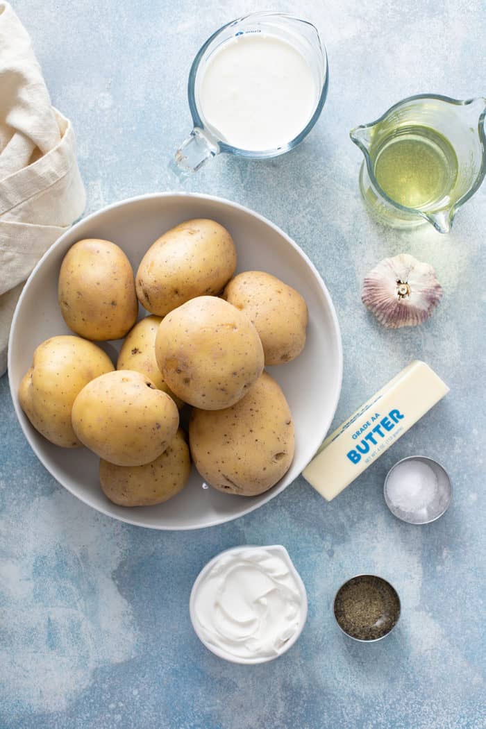 Ingredients for garlic mashed potatoes on a blue countertop