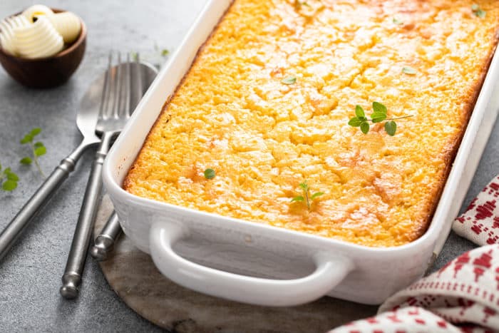 Close up of baked jiffy corn casserole in a white baking dish