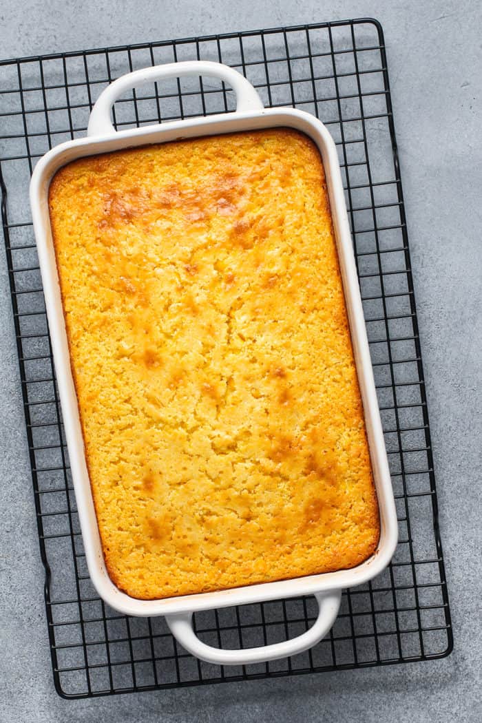 Overhead view of a white baking dish filled with jiffy corn casserole set on a wire cooling rack