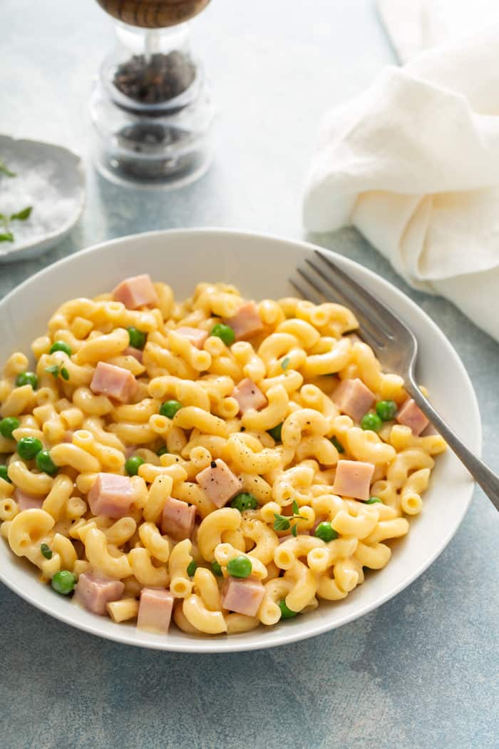 Bowl of one pot macaroni and cheese with peas and ham added to it
