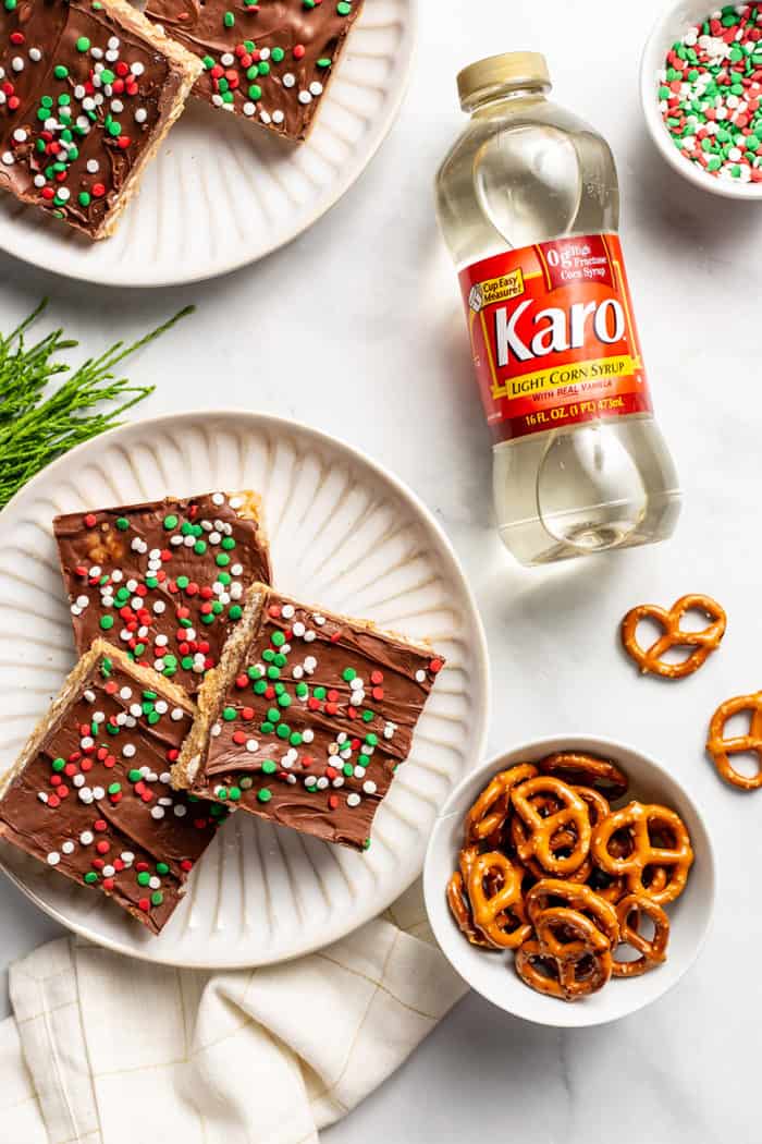 Plate of peanut butter pretzel bars decorated with festive sprinkles next to a bottle of Karo corn syrup