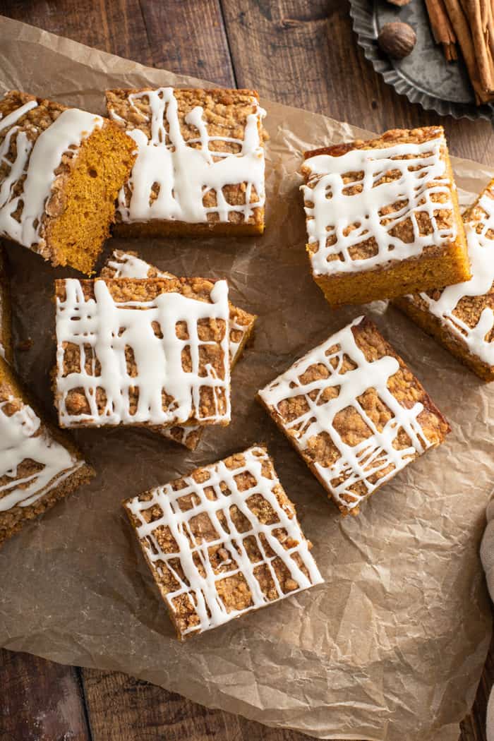 Overhead view of several slices of pumpkin coffee cake scattered on a piece of parchment paper