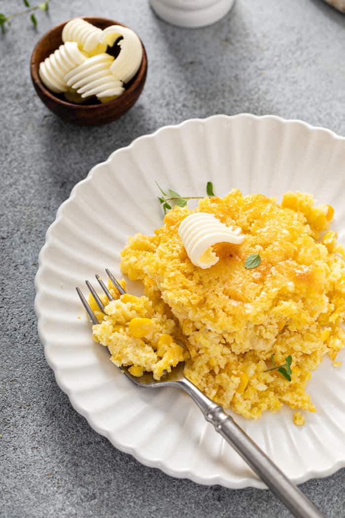 Fork next to a portion of jiffy corn casserole on a white plate