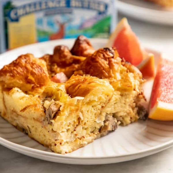 Slice of croissant breakfast casserole and two pieces of grapefruit on a white plate