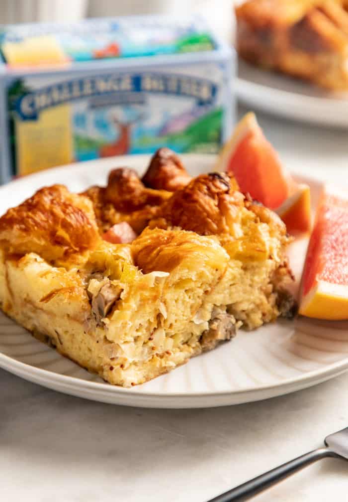 Slice of croissant breakfast casserole and two pieces of grapefruit on a white plate