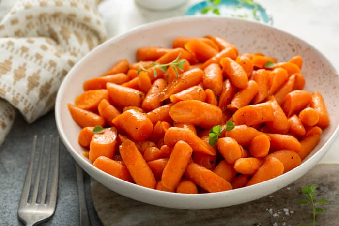 Bowl of honey glazed carrots garnished with fresh thyme