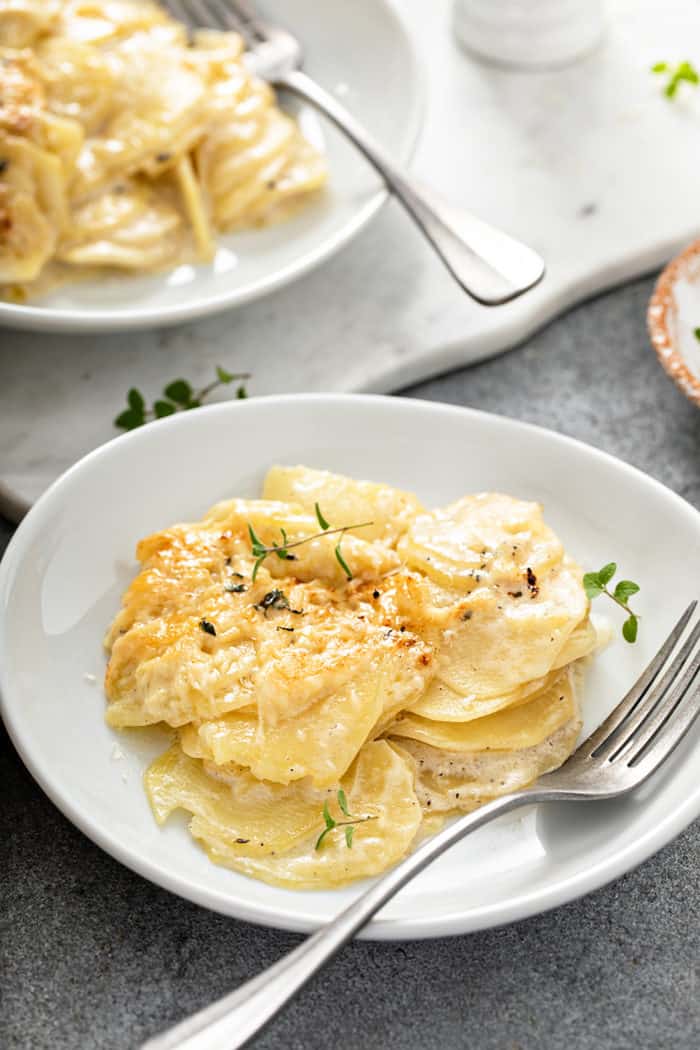 White plate with a serving of potato gratin. A second plate is in the background