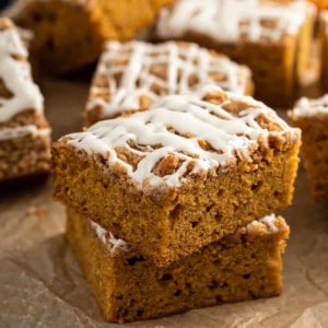 Two pieces of pumpkin coffee cake stacked on a piece of parchment paper