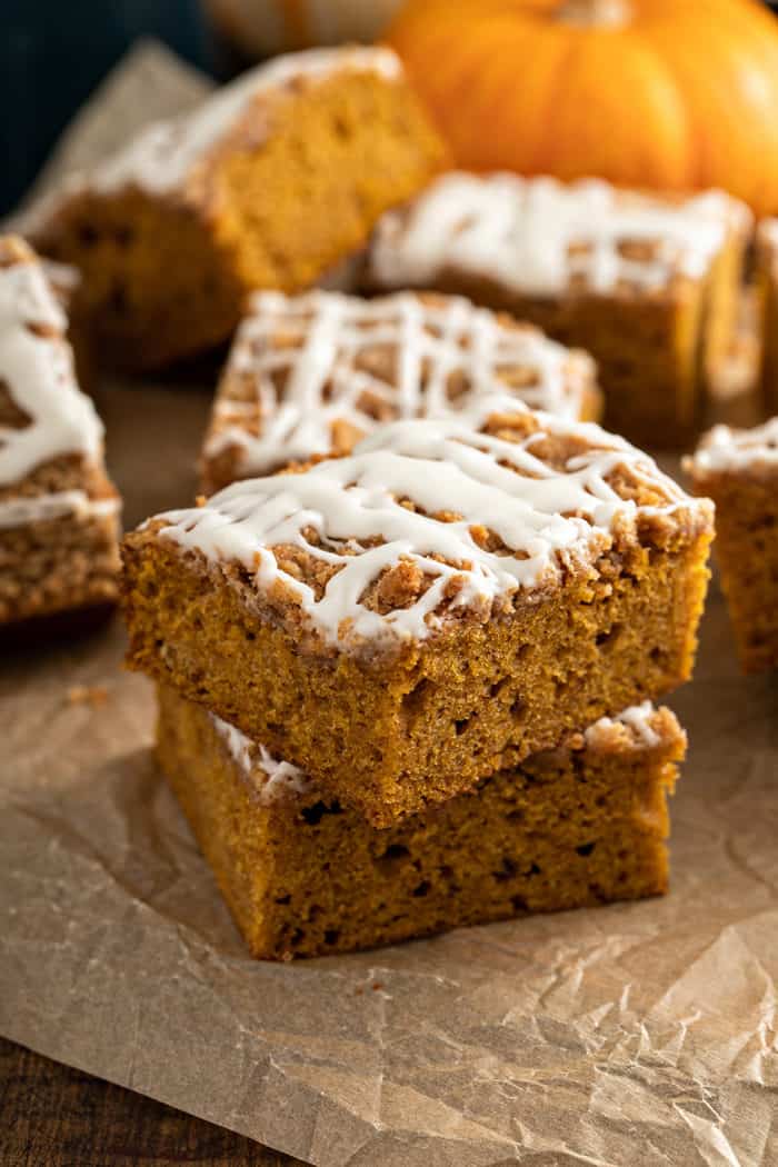 Two pieces of pumpkin coffee cake stacked on a piece of parchment paper