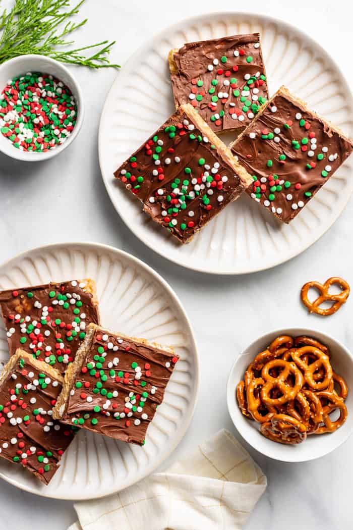 Overhead view of two white plates, each containing three peanut butter pretzel bars