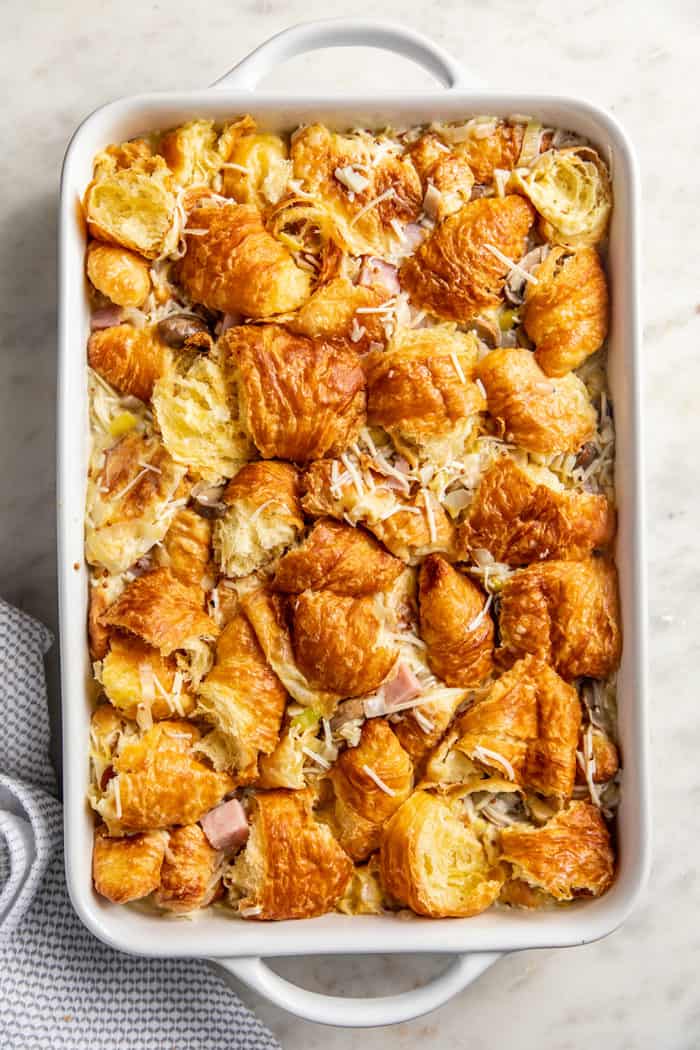 Unbaked croissant breakfast casserole in a white baking dish set on a marble countertop