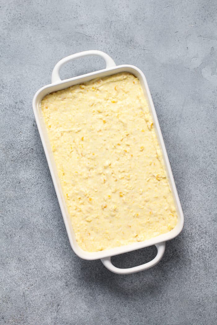 Unbaked jiffy corn casserole in a white baking dish, ready to go in the oven