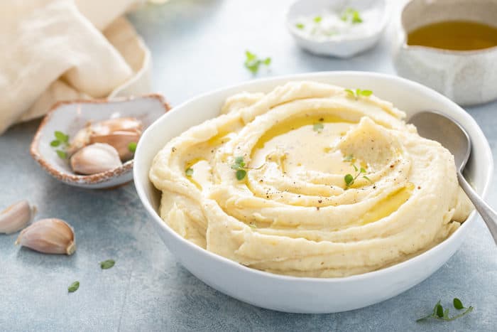 White serving bowl filled with garlic mashed potatoes on a blue countertop