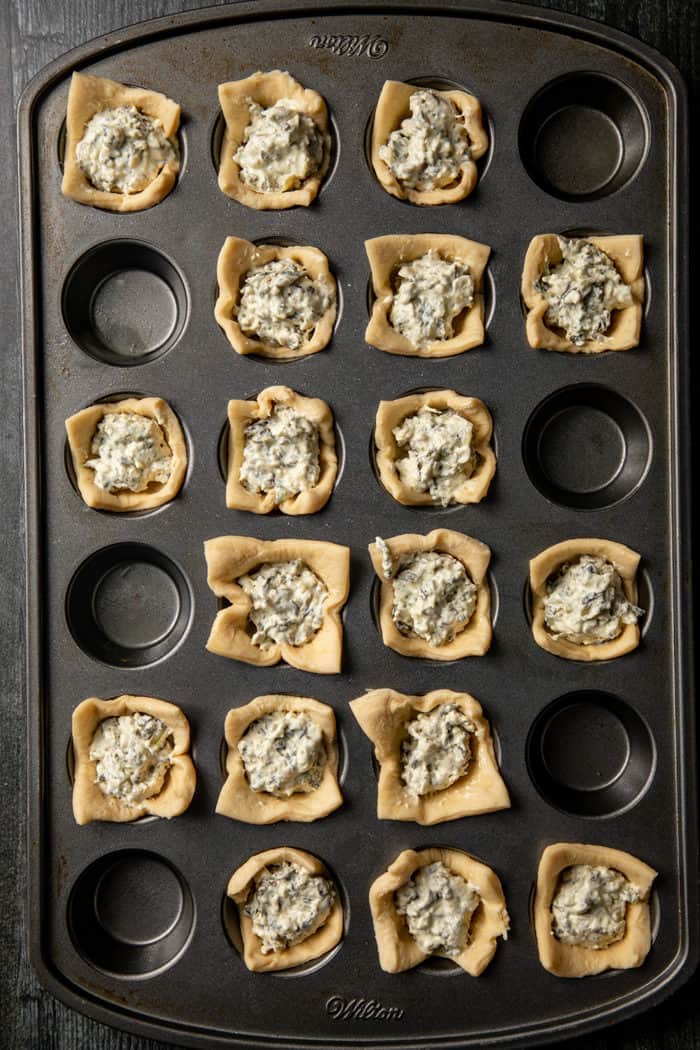 Spinach artichoke bites in a mini muffin tin, ready to be baked