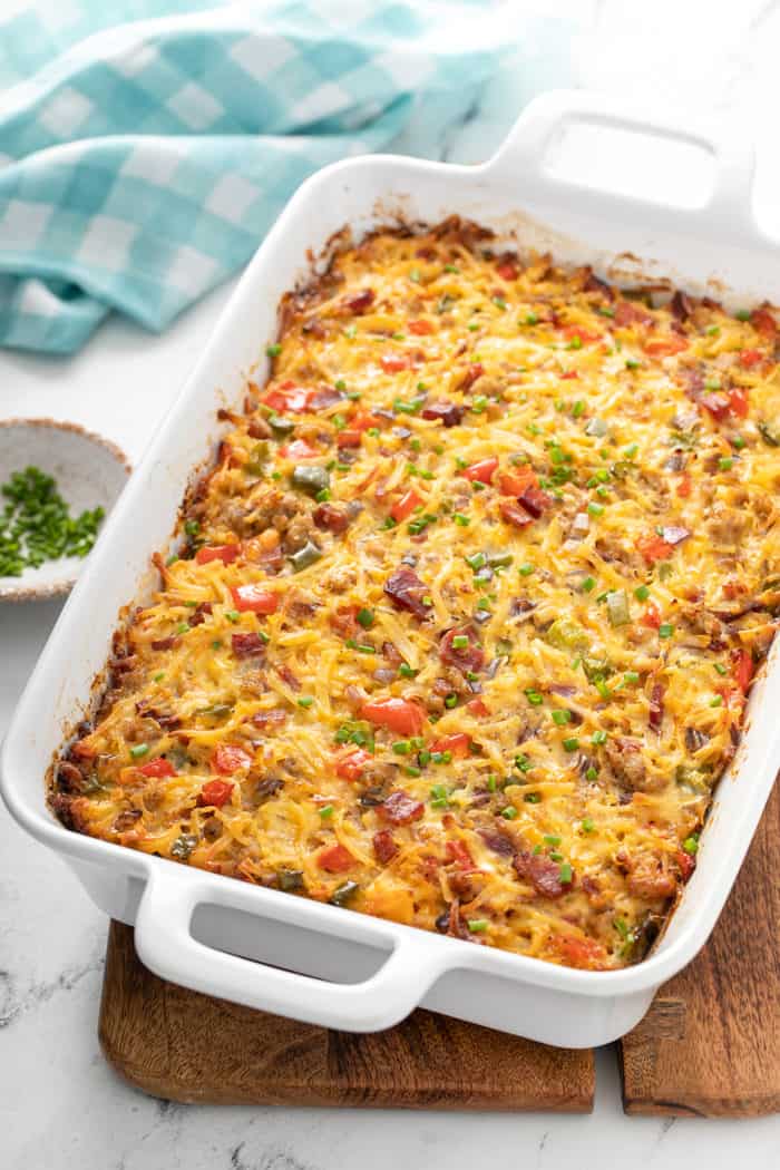 Baked hash brown breakfast casserole in a white baking dish, set on a wooden trivet