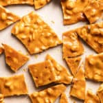 Broken pieces of peanut brittle on a baking sheet