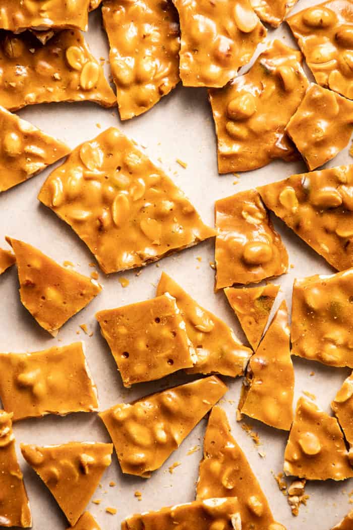 Broken pieces of peanut brittle on a baking sheet